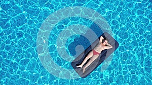 boy lying on inflatable mattress in the swimming pool, aerial view