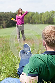 Boy lying on meadow and looking at his girlfriend