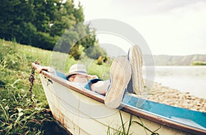 Boy lying in old boat near the lake