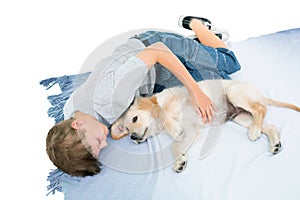 Boy lying with puppy on blanket over white background