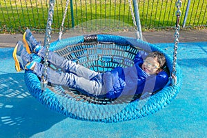 Boy lying on swing at palyground photo