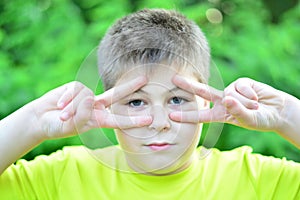 The boy made glasses around his eyes with his fingers