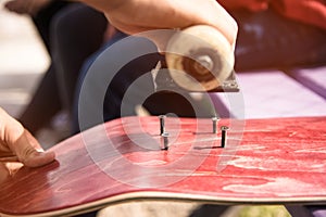 Boy makes bolt holes on the griptape on a skateboard