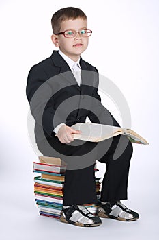 Boy makes homework sitting on stack of books