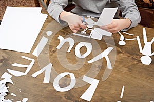 Boy makes origami - car and family, children, parent, I love you text, top view on wood background