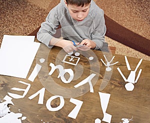 Boy makes origami - car and family, children, parent, I love you text, top view on wood background