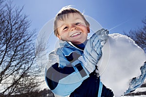 Boy is making a big snowball in the mountains, winter fun