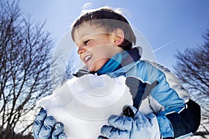 Boy is making a big snowball in the mountains, winter fun