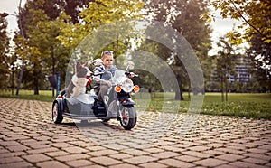 Boy making frowning face on a electrical bike, driving a dog in sidecar