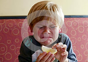 Boy making a funny face after biting a lemon