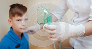 Boy making inhalation with nebulizer at clinic.