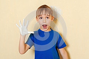 Boy making print of his hand on the wall. Kid painting wall at home