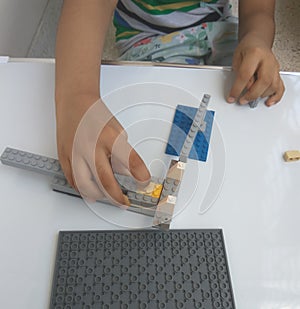 A boy making a toy with plastic lego blocks.
