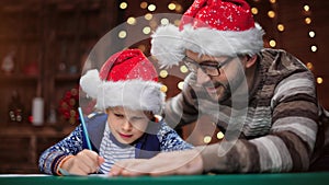 Boy and male parent writing wishes list letter at Christmas eve. Shot on RED Raven 4k Cinema Camera