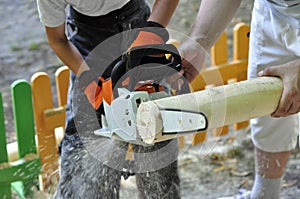 Boy and man with chainsawÃÂ  sawing wood