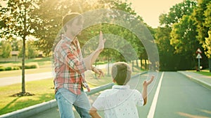 Boy and man dancing in park. Joyful father and son giving high five outdoors