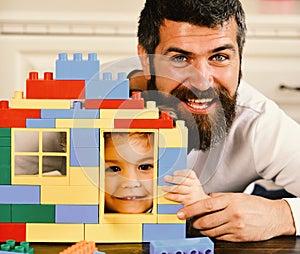 Boy and man on defocused background. Father and son with smiling faces hold toy bricks construction