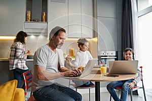 Boy and man sitting before laptops while woman cooking