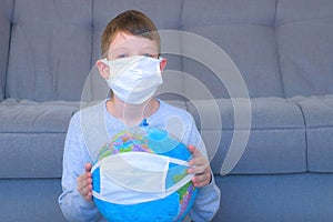 Boy in mask holding globe in mask in hands, pandemic and quarantine.