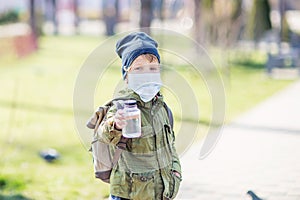 A boy in mask holds a bottle of water in hand