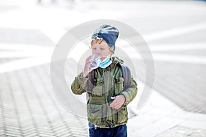A boy in mask holds a bottle of water in hand