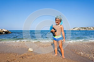 Boy with mask and paddles stands on the seashore