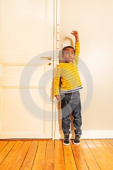 Boy measuring his height benchmark on door at home