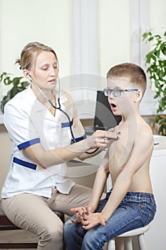 Boy during the medical examination with a stethoscope by the pediatrician deeply breathes through the open mouth.