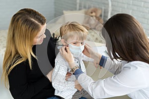 A boy in a medical mask at a doctor& x27;s appointment.