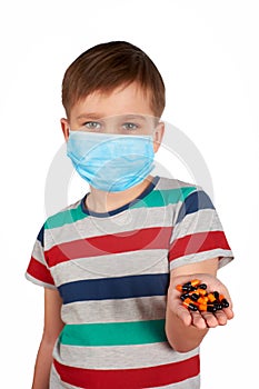 A boy in a medical mask holds out his hand, in which there are tablets from the virus. Isolated on a white background