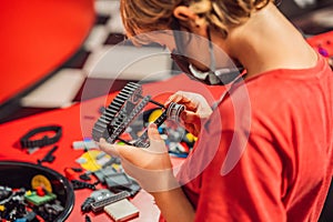 A boy in a medical mask plays with a constructor. child playing and building with colorful plastic bricks table. Early