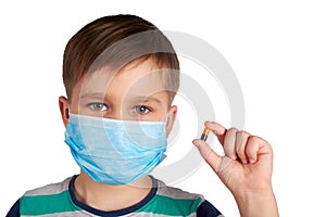 Boy in a medical mask shows a pill. Isolated on a white background. coronavirus concept.