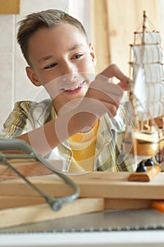 Boy with model of ship and handsaw