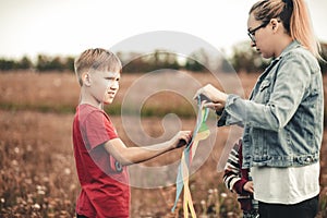 Boy with mom fly a kite on summer day in the meadow outdoor. Summer activity