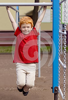 Boy on monkey bars. Little boy hanging on gym activity center of school playground. Outdoor activity for kids. Sport