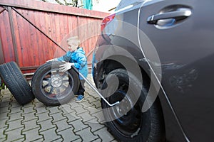 Boy mounted tires on a car.