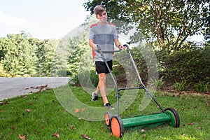 Boy mowing grass with push reel mower