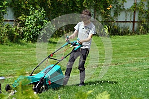 Boy mowing the lawn with lawnmower