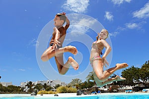 Boy with mum jumping into pool smiling