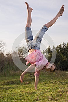 Boy in nature, doing a one-hand handstand.