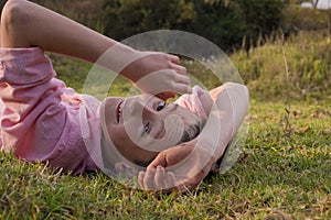 Boy in nature, lying on grass and looking at the camera