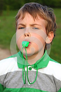 Boy on nature, plays, whistles in green whistle