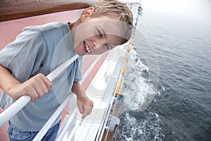 Boy near handrails on deck of ship photo