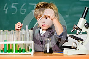 Boy near microscope and test tubes in school classroom. Science concept. Gifted child and wunderkind. Kid study