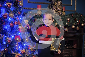 The boy next to a glowing blue Christmas tree and fireplace