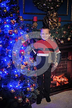 The boy next to a glowing blue Christmas tree and fireplace