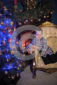 The boy next to a glowing blue Christmas tree and fireplace