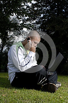 Boy with notebook and cell phone in park