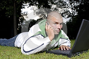 Boy with notebook and cell phone in park