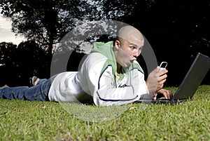 Boy with notebook and cell phone in park